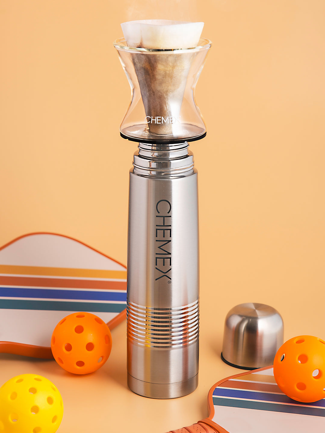 Funnex on the go, brewing coffee into a thermos with pickleball rackets and balls