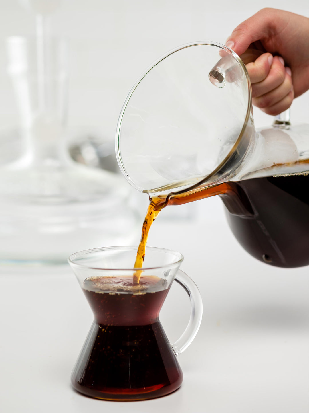 Glass handle coffeemaker pouring coffee into a glass handle mug