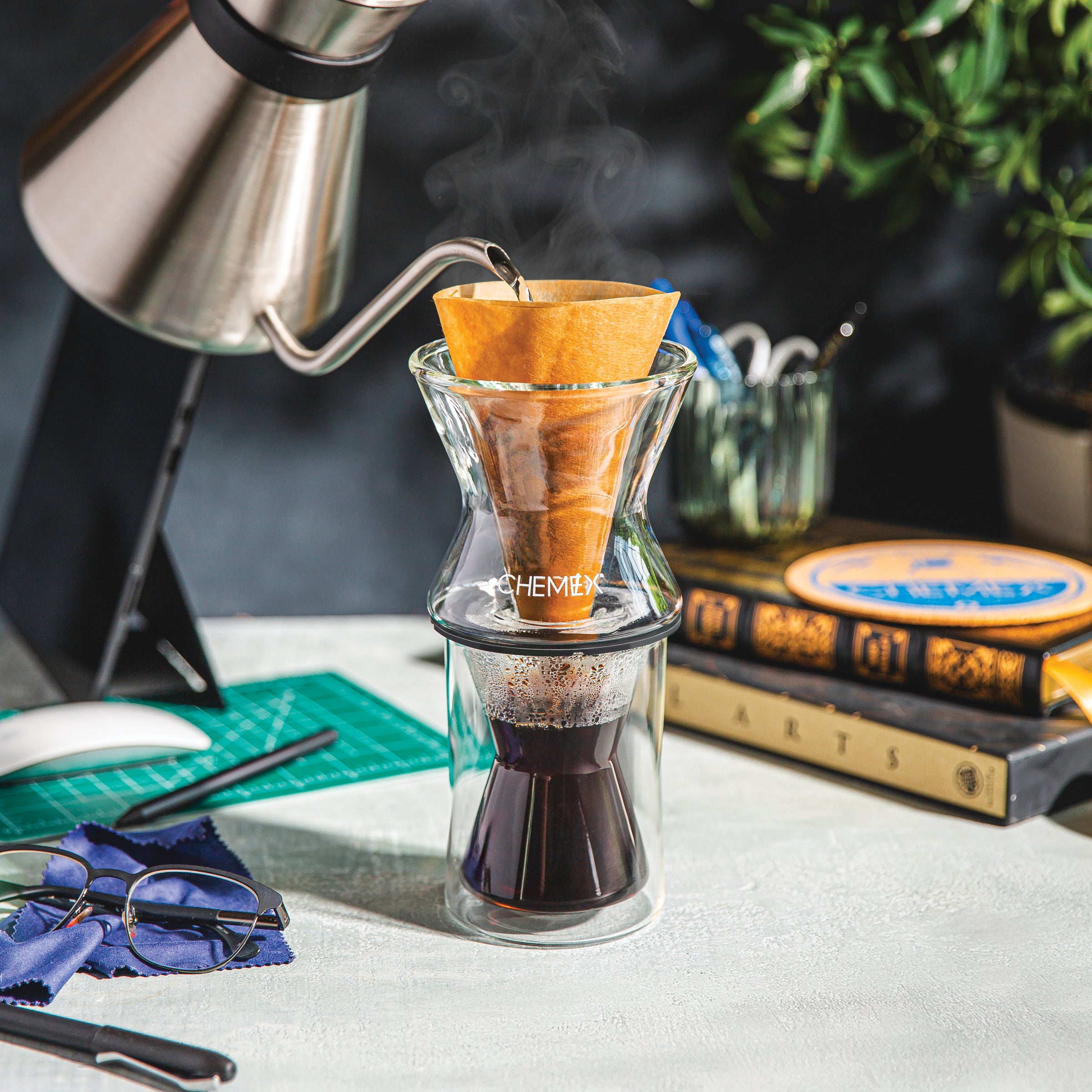 Brewing coffee with the CHEMEX Funnex into the double walled mug. Background is a desk setting. Afternoon coffee break.