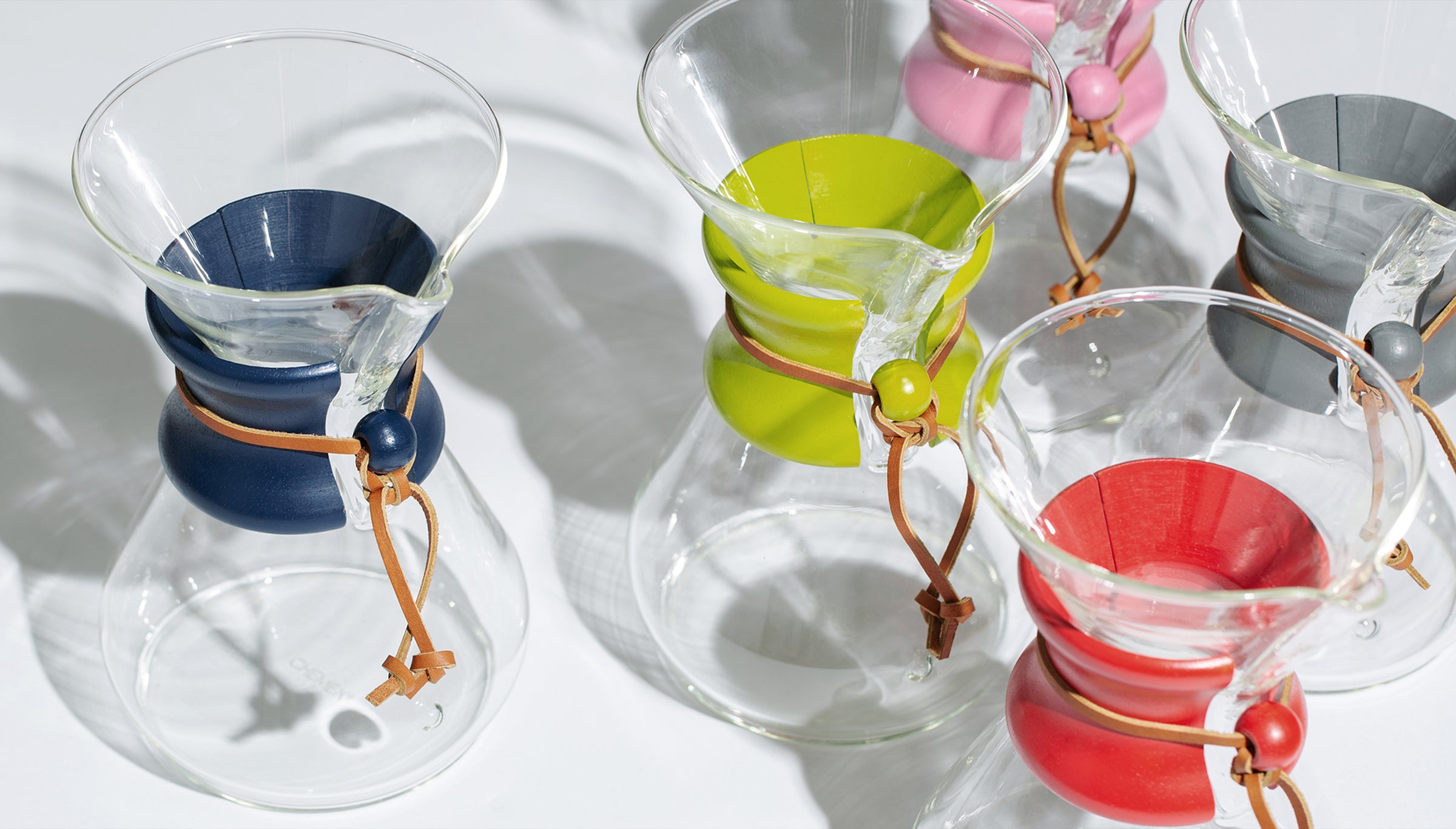 Looking down on Chemex coffeemakers each with a different color painted collar and bead