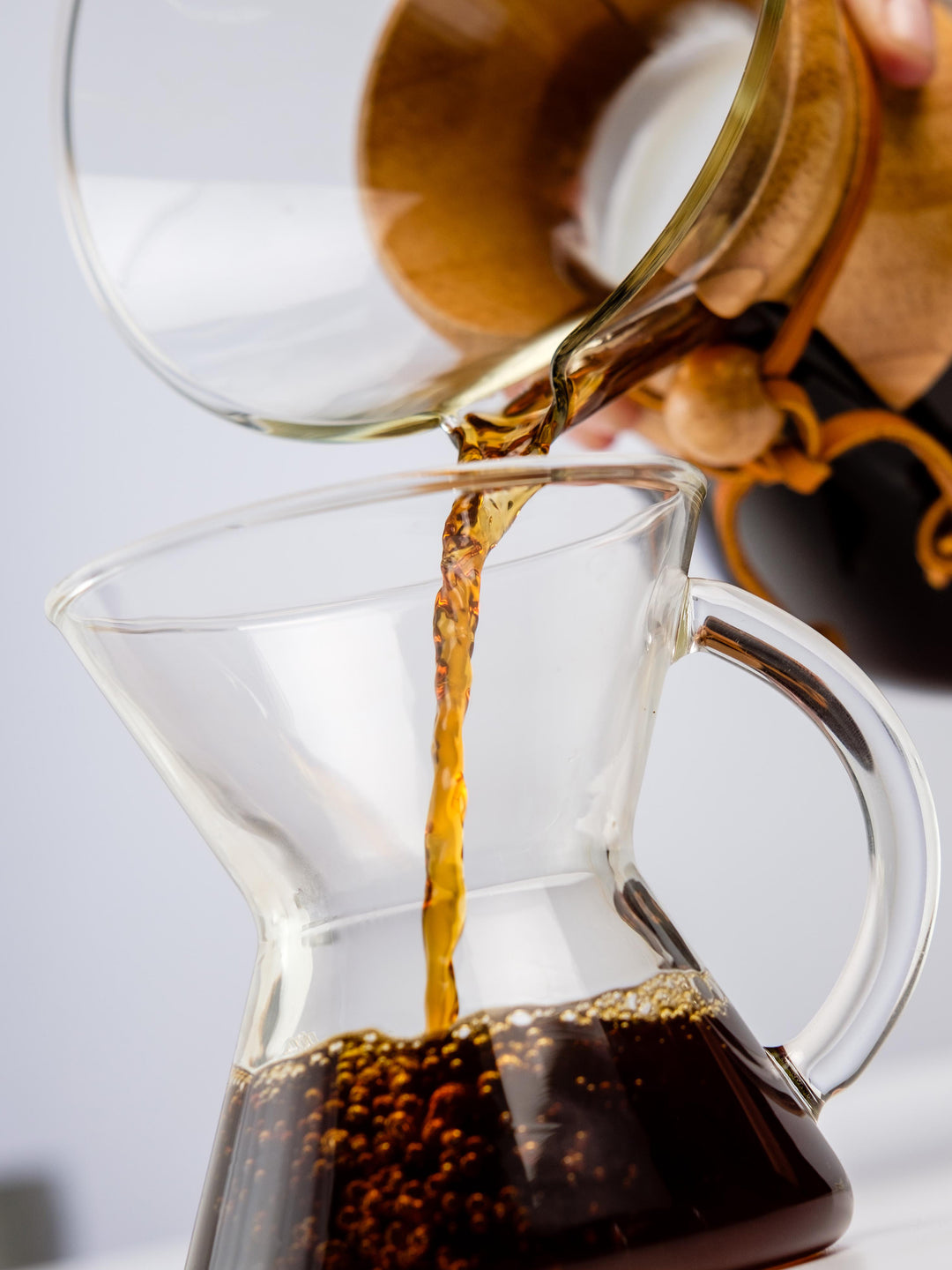 close-up photo of coffee being poured into a glass handle mug