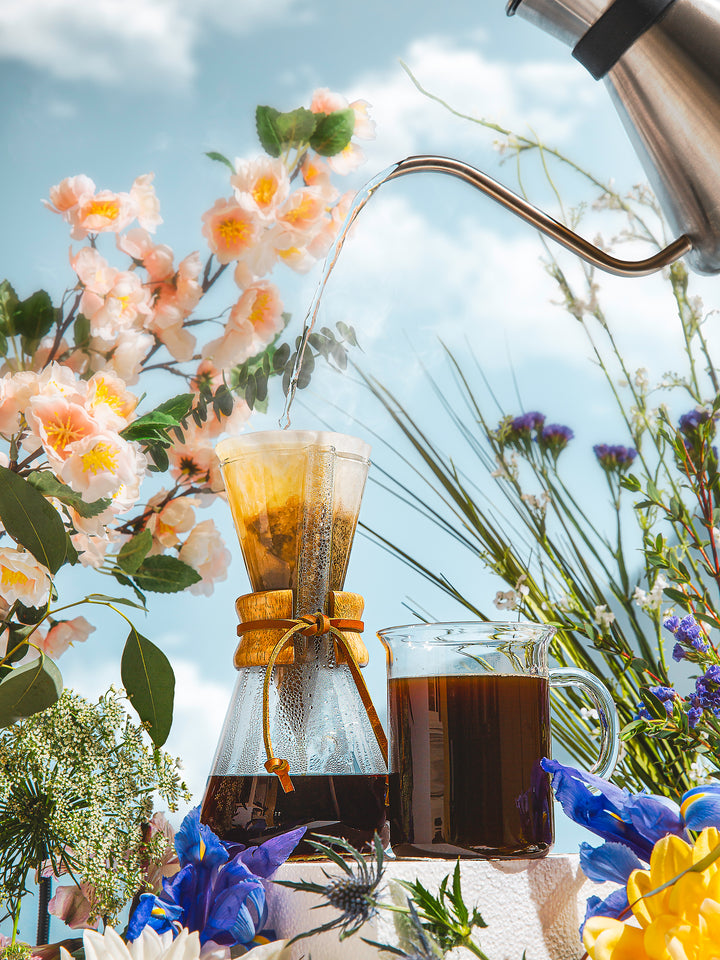 The chemex Chettle brewing a Three Cup Classic CHEMEX with a bright summer background surrounded by flowers.