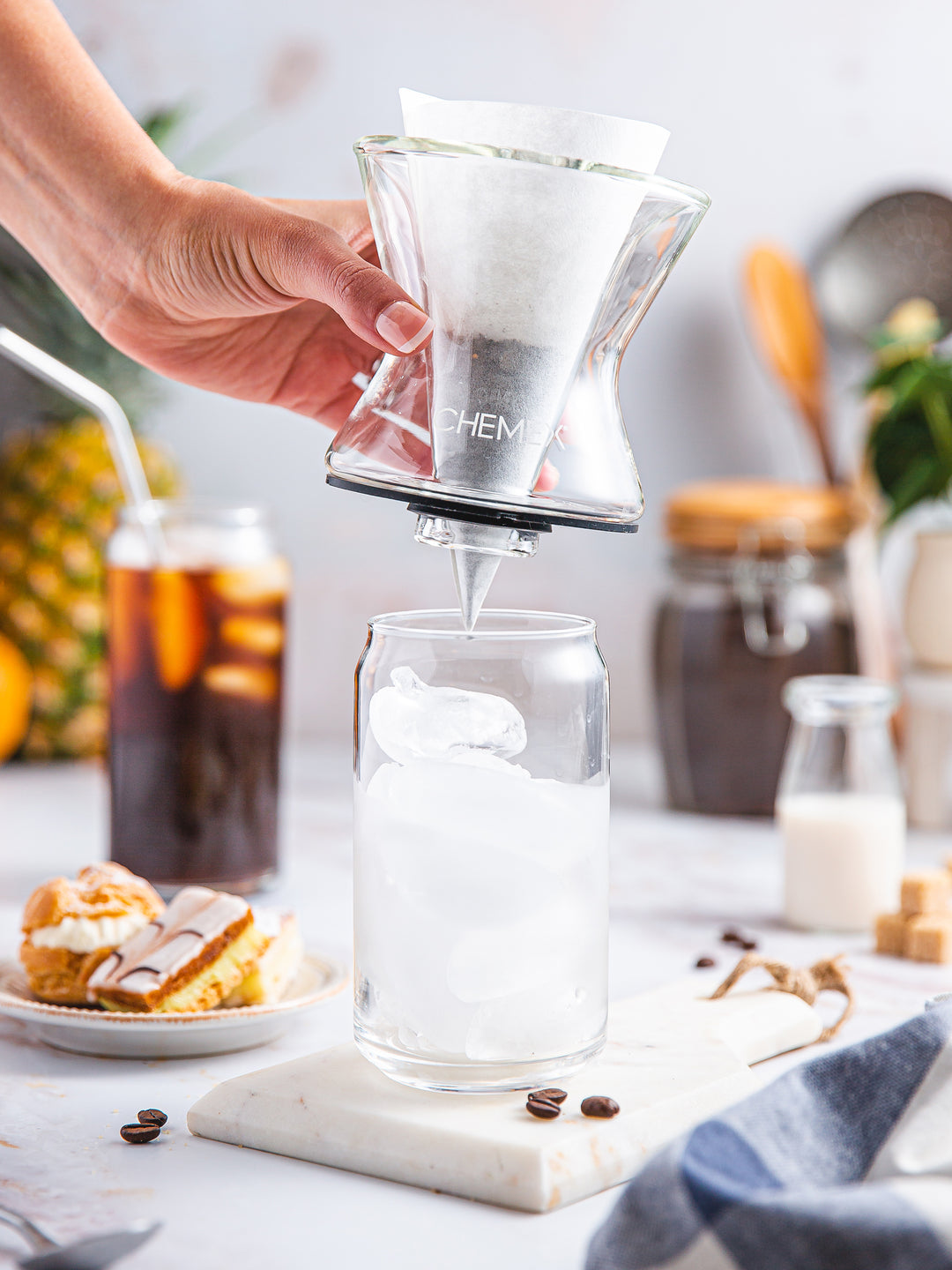 A hand placing the Funnex coffeemaker on a glass cup full of ice to brew iced coffee