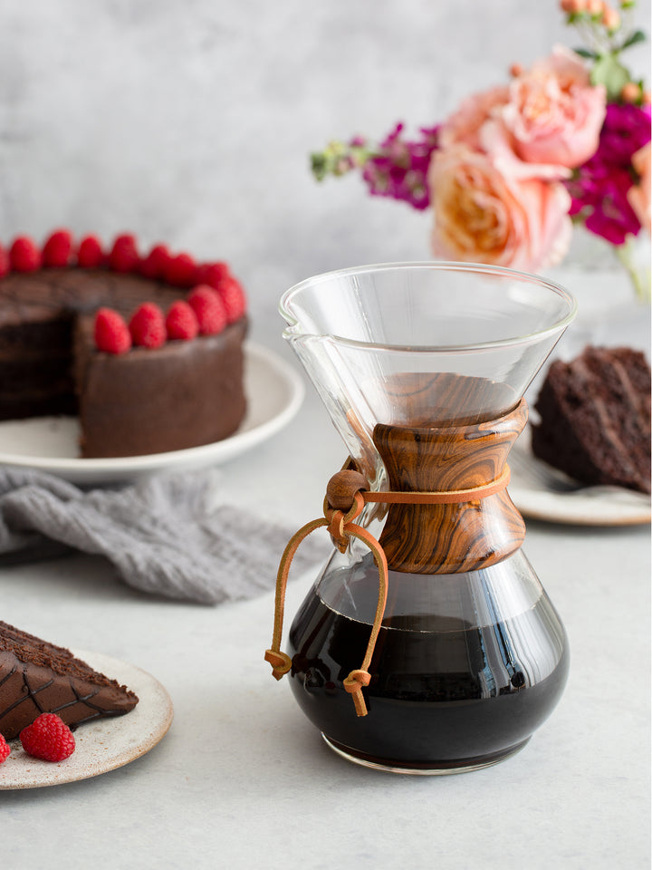 Tiger CHEMEX Collar on a six cup classic chemex full of coffee, surrounded by delicious chocolate cake.