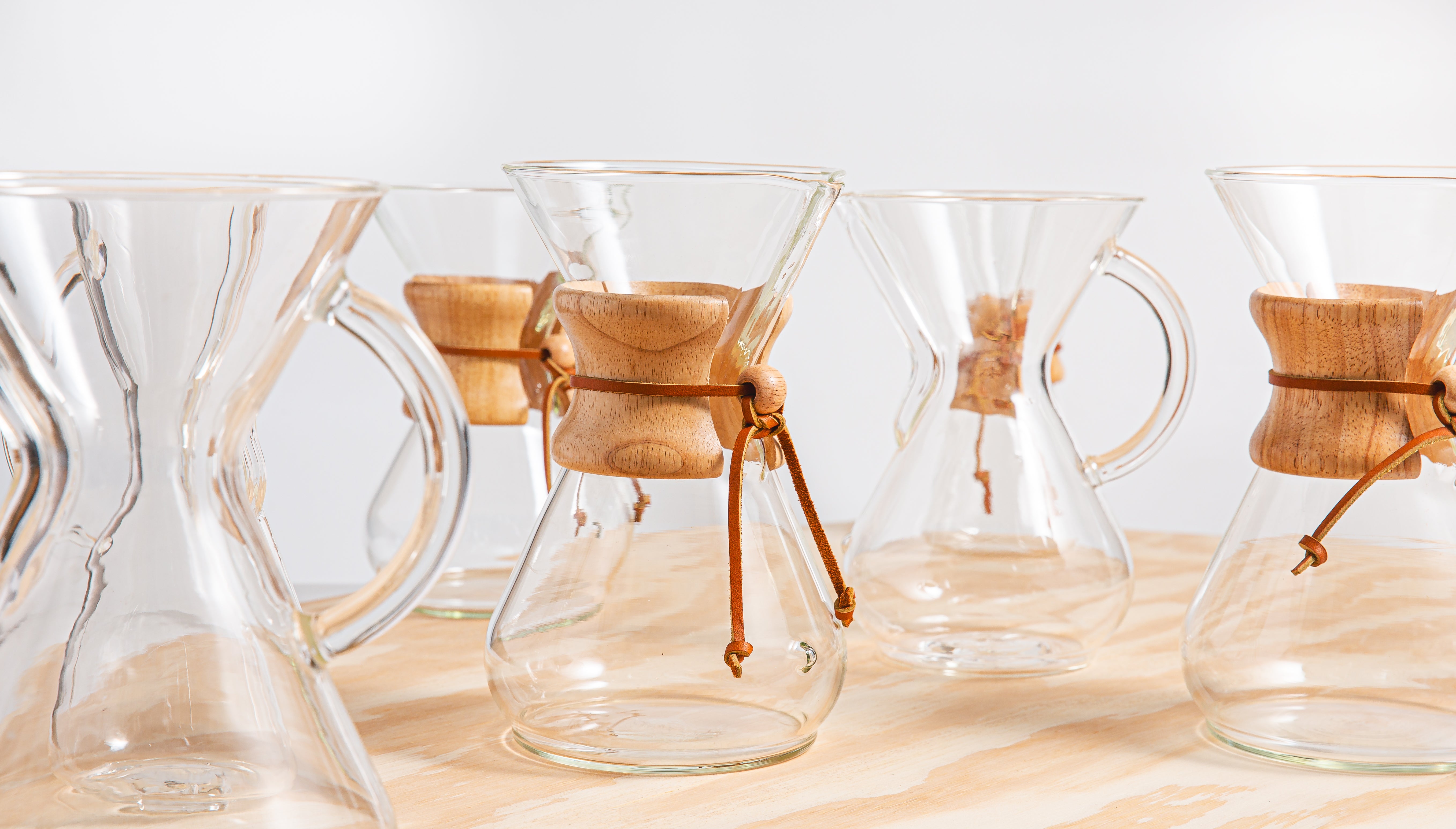 Series of coffeeemakers lined up next to each other on a wooden table