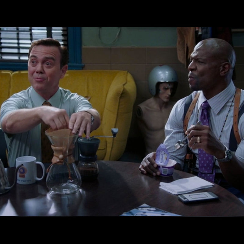 A scene from Brooklyn nine nine depicts a character brewing coffee using a Chemex pour-over carafe.
