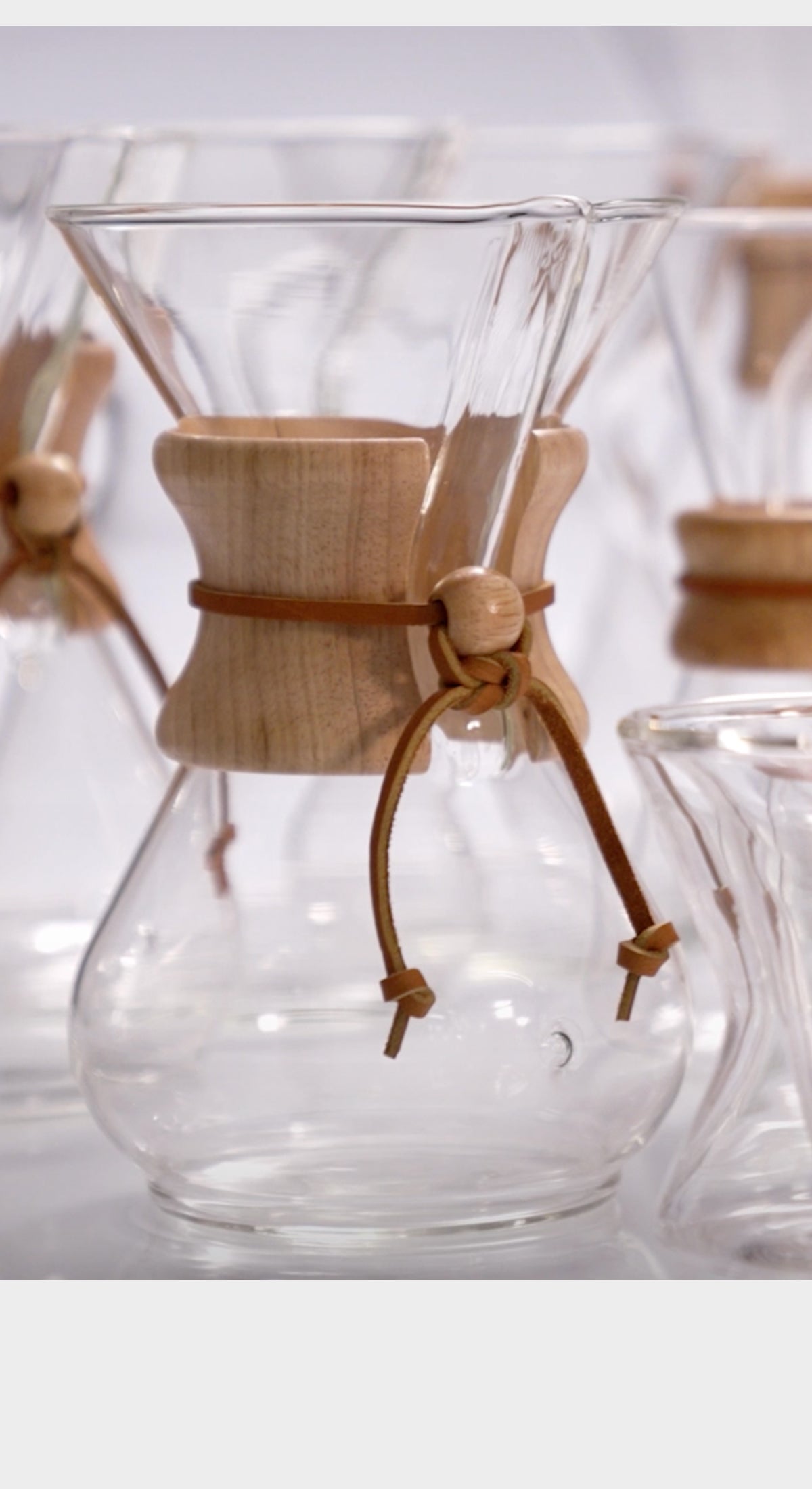 Close-up of a glass coffee maker with wooden collar on a white background