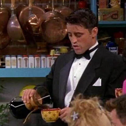  character Joey Tribbiani from Friends pouring coffee into a distinctive yellow spotted cup from a Chemex pour-over brewer.