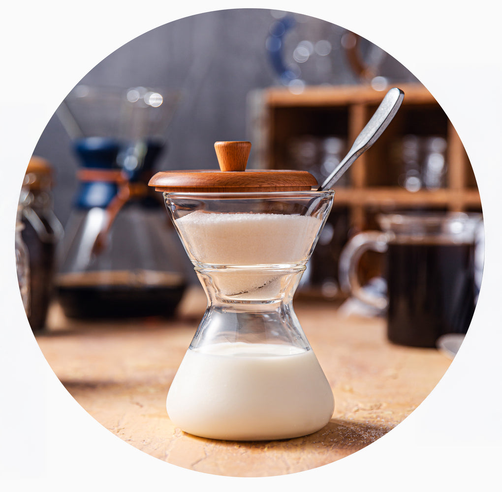 chemex cream and sugar set on a counter, in the background is a chemex brewer and mugs
