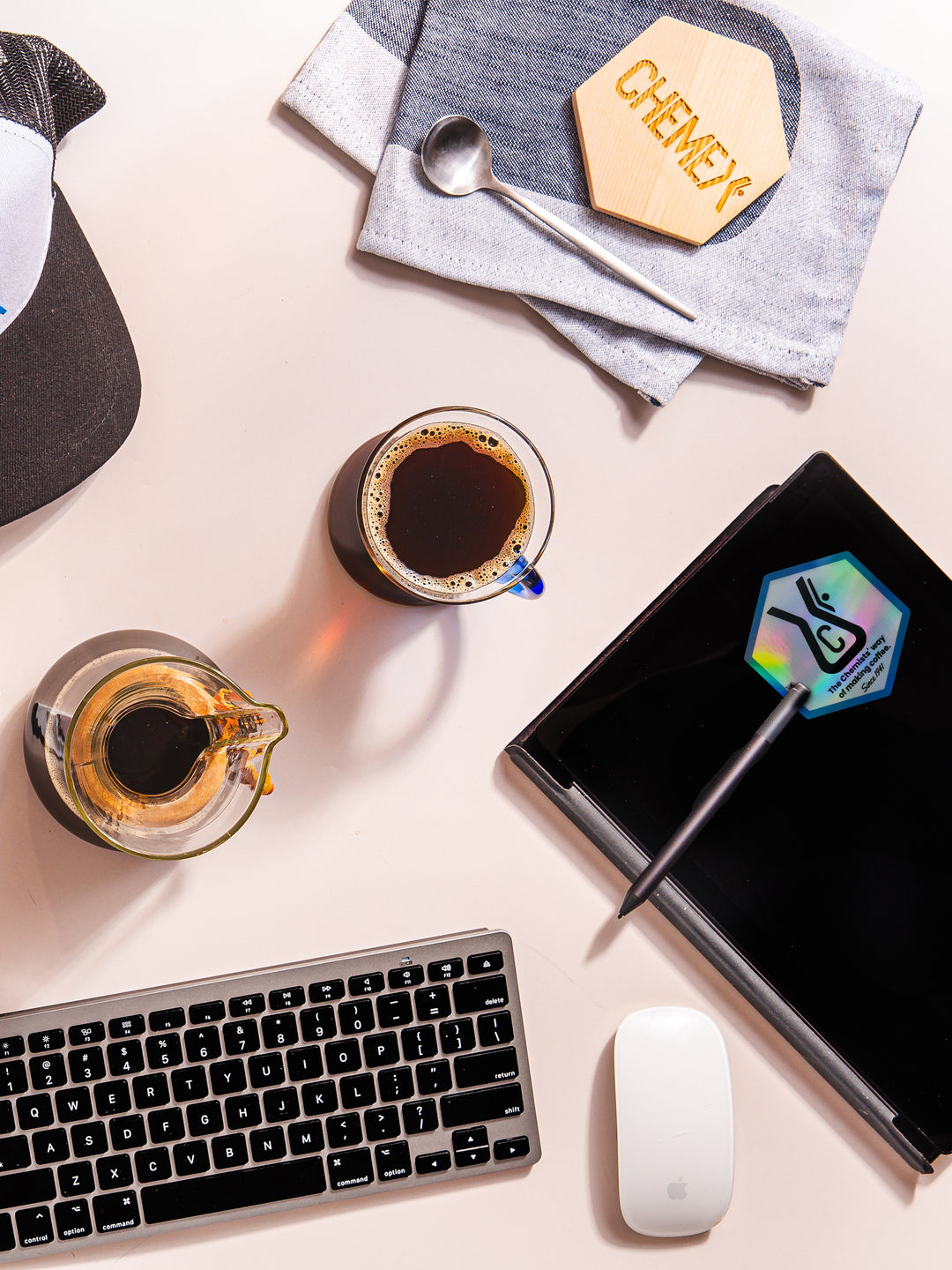 Chemex chemist holographic sticker stuck on a notebook which is sitting on a desk with chemex coffee and blue handle glass mug 