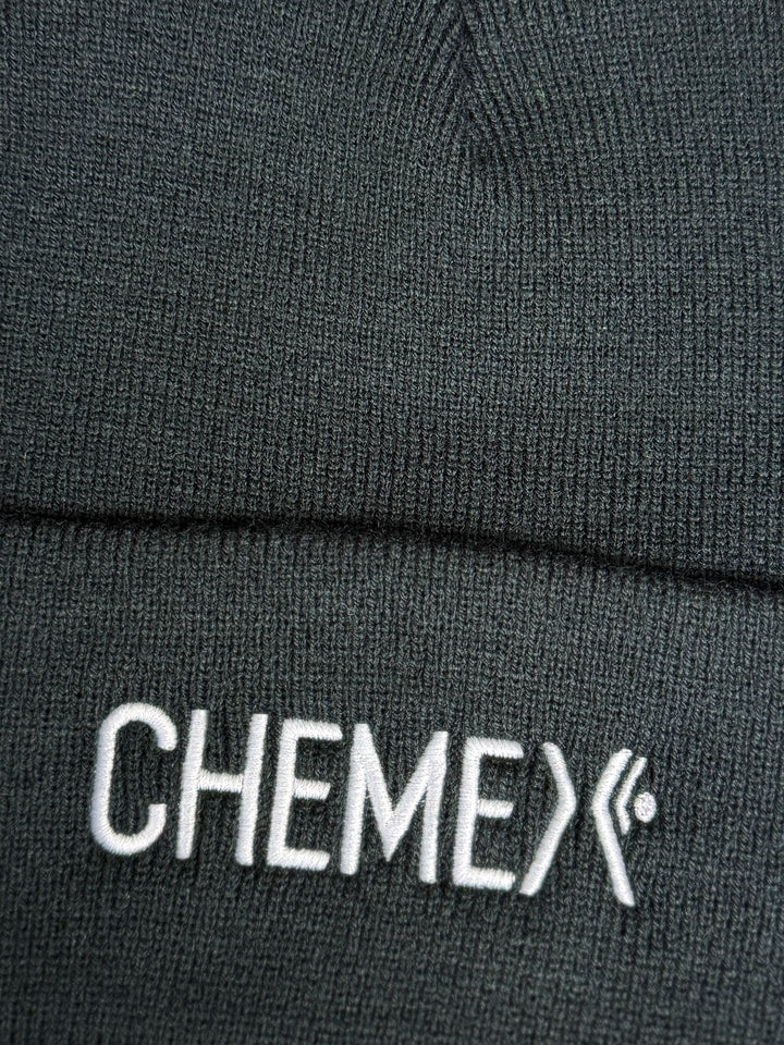 Close-up of a black beanie with 'CHEMEX' logo on a dark background